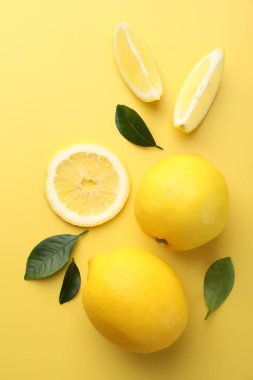 Sarı arka planda taze olgun limonlar, düz uzanmış.