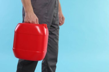 Açık mavi arka planda plastik kutu tutan adam, yakın plan. Metin için boşluk