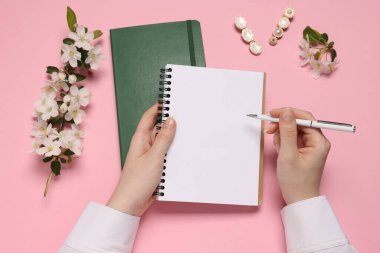 Ajandası ve pembe arka planda çiçekleri olan bir kadın.