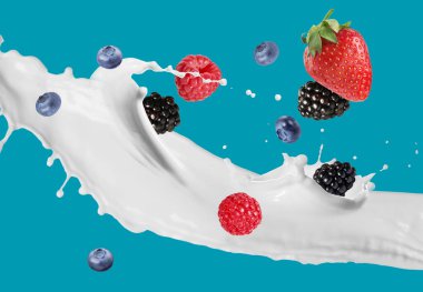 Süt sıçraması ve mavi arka planda farklı taze meyveler.
