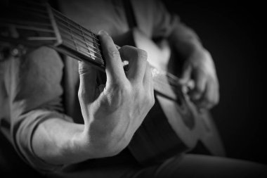Karanlıkta gitar çalan adam, yakın plan. Siyah ve beyaz etkisi