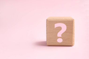 Pembe arka planda soru işareti olan tahta küp, yakın plan. Metin için boşluk