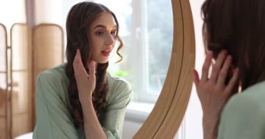 Güzel bir kadın aynada kendine bakıyor.