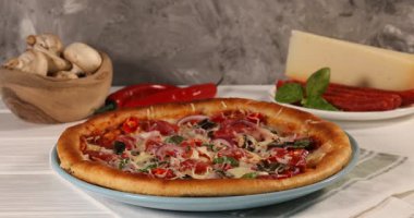 Beyaz ahşap masada ince füme sosisli pizza yiyen bir kadın.