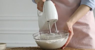 Masada el çırpma makinesiyle krem çırpan bir kadın, yakın plan. Metin için boşluk