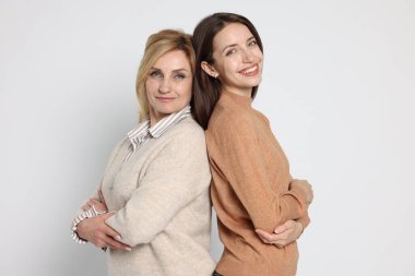 Neşeli anne ve kızı arka arkaya beyaz arka planda