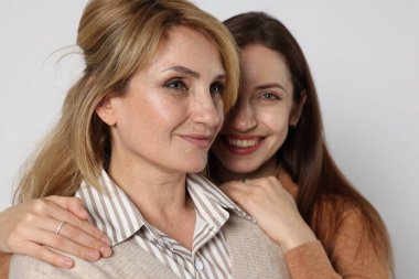 Beyaz arka planda annesine sarılan bir kadın.