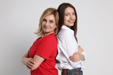 Neşeli anne ve kızı arka arkaya beyaz arka planda