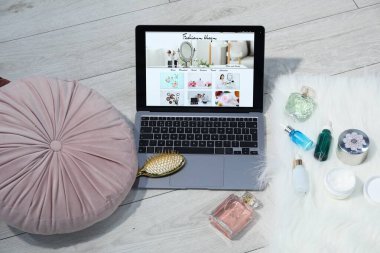 Moda blog siteli dizüstü bilgisayar, parfümler, kozmetik ürünler ve iç mekanda fırça, üst görünüm