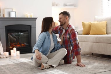 Evdeki şöminenin yanında oturan mutlu çift.