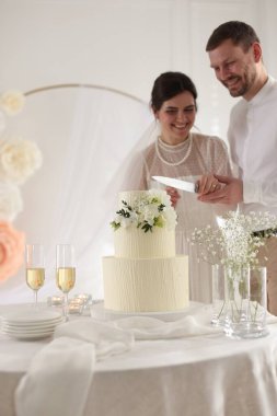 Evli çift evde bıçakla lezzetli düğün pastası kesiyor.