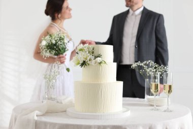 Evde evli bir çift, masadaki düğün pastasına odaklanıyor.