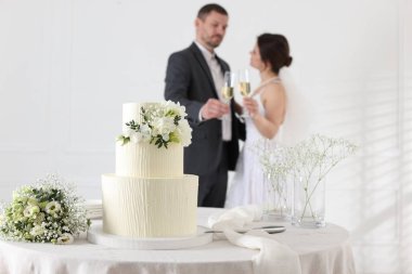 Mutlu evli çift içeride, düğün pastasına ve masadaki bukete odaklan.