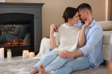 Evdeki şöminenin yanında oturan sevimli çift.