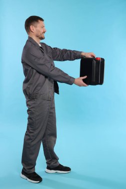 Açık mavi arka planda plastik kutu tutan adam.