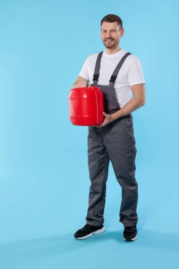 Açık mavi arka planda plastik kutu tutan adam.