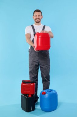 Açık mavi arka planda plastik kutuları olan bir adam.