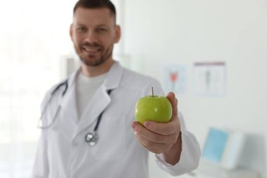 Klinikte yeşil elmalı ve steteskoplu beslenme uzmanı, seçici odaklı.