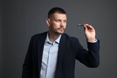 Hedef alınıyor. Gri arkaplanı hedefleyen dartlı adam.