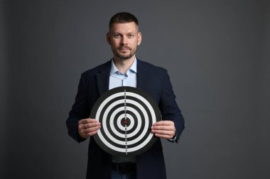 Hedef alınıyor. Gri arka planda dart tahtası olan adam.