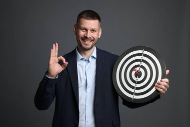 Hedef alınıyor. Ok ve dart tahtası olan adam gri arka planda iyi bir hareket gösteriyor.