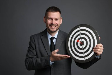 Hedef alınıyor. Dart tahtası ve gri arka planda oku olan bir adam.