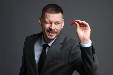 Hedef alınıyor. Gri arkaplanı hedefleyen dartlı adam.