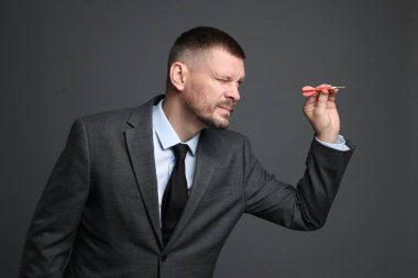 Hedef alınıyor. Gri arkaplanı hedefleyen dartlı adam.