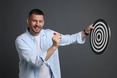 Hedef alınıyor. Dart tahtası ve gri arka planda oku olan bir adam.