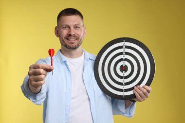 Hedef alınıyor. Sarı arka planda ok ve dart tahtası olan adam.