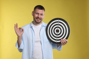 Hedef alınıyor. Dart tahtası olan adam sarı arka planda iyi bir hareket gösteriyor.