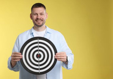 Hedef alınıyor. Sarı arkaplanda dart tahtası olan adam, metin için boşluk