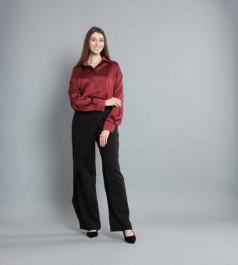 Gri arka planda şık giyinmiş güzel bir kadın.