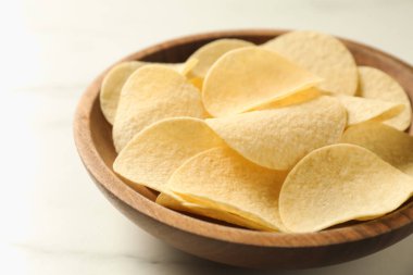 Lezzetli patates cipsleri beyaz mermer masada, yakın plan.