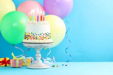 Renkli şekerli nefis bento keki ve açık mavi masada yanan mumlar. Metin için boşluk