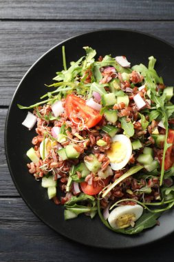 Siyah ahşap masada kahverengi pirinçli nefis bir salata.