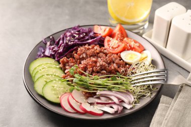 Gri masada servis edilen kahverengi pirinçli lezzetli salata, yakın plan.