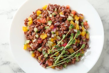 Beyaz mermer masada kahverengi pirinçli lezzetli bir salata.