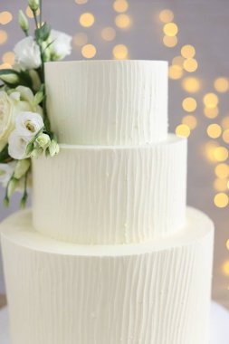 Gri arka planda çiçeklerle süslenmiş enfes düğün pastası. Bulanık ışıklar, yakın plan.