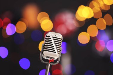 Karanlık arka planda bulanık ışıkları olan klasik mikrofon, mesaj için yer. Müzik ekipmanları