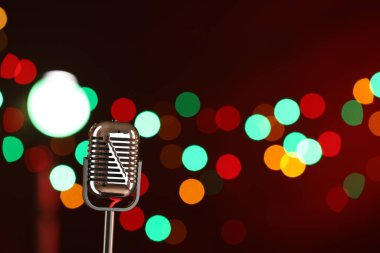 Koyu kırmızı arka planda, bulanık ışıkları olan klasik mikrofon, mesaj için yer. Müzik ekipmanları