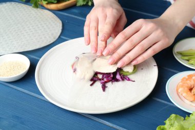 Mavi ahşap masada nefis börek yapan bir kadın, yakın plan.