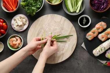 Koyu gri masada nefis börek yapan bir kadın.