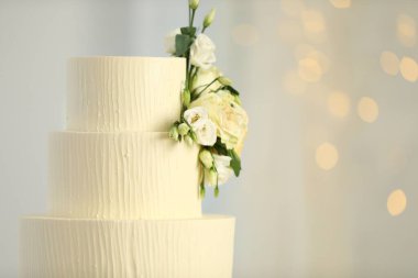 Bulanık arkaplanda çiçek dekoru olan nefis düğün pastası, mesaj için yer. Bokeh etkisi