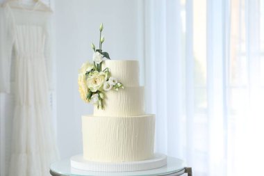 İçerideki masada çiçeklerle süslenmiş nefis düğün pastası.