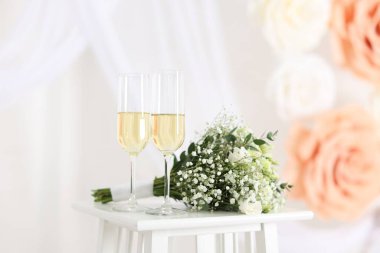 Şampanya bardakları ve düğün buketi kapalı bir masada.