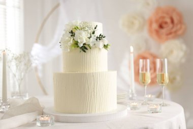 Çiçek desenli nefis düğün pastası ve kapalı bir masada şampanya bardakları.