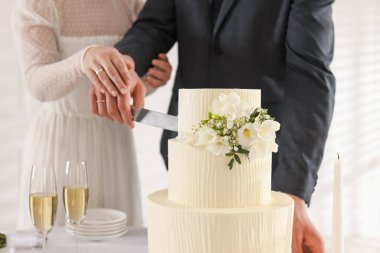 Yeni evliler düğün pastasını içeride kesiyorlar, yakın plan.