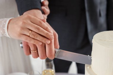 Yeni evliler düğün pastasını içeride kesiyorlar, yakın plan.