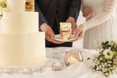 Yeni evliler, bir parça düğün pastasıyla tabağı evin içindeki masaya koyuyorlar.